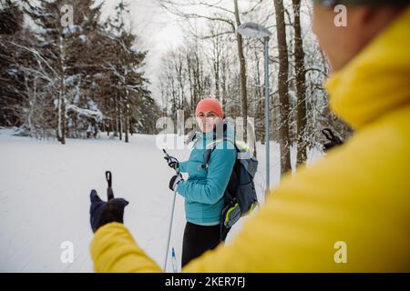 Vue arrière d'un couple senior qui skine ensemble au milieu de la forêt. Banque D'Images