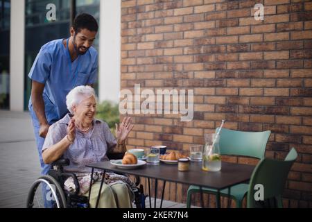Soignant prenant le petit déjeuner avec son client au café. Banque D'Images