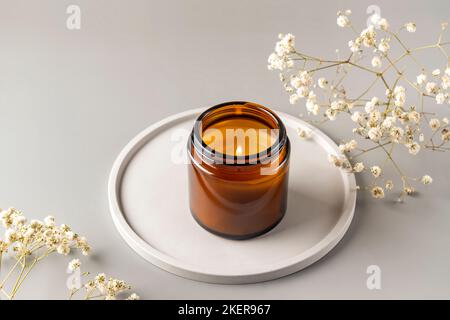 Bougie de soja bio parfumée dans un pot en verre foncé sur plateau en céramique concept minimaliste. Gros plan, espace de copie pour le texte. Concept de minimalisme zéro gaspillage, handma Banque D'Images