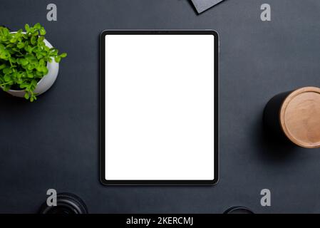 Maquette de tablette sur table noire entourée d'objets. Affichage isolé en blanc pour la promotion de la conception d'applications ou de sites Web. Vue de dessus, composition de la pose à plat Banque D'Images