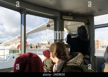 Touristes regardant par les fenêtres d'un bateau de la Tamise City Cruises aux sites et monuments de Londres, ici le Millenium Bridge - Londres, Royaume-Uni Banque D'Images