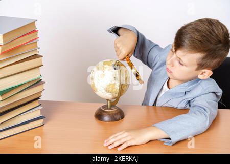 Concept d'éducation. L'étudiant fait ses devoirs, étudie le monde entier. Il a des livres des deux côtés. Banque D'Images