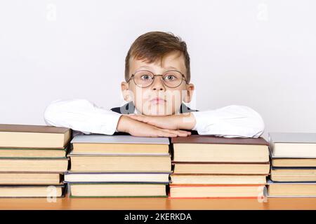 Concept d'éducation. L'étudiant s'est posé sur des livres empilés de suite, en regardant l'appareil photo. Isolé sur fond blanc. Banque D'Images