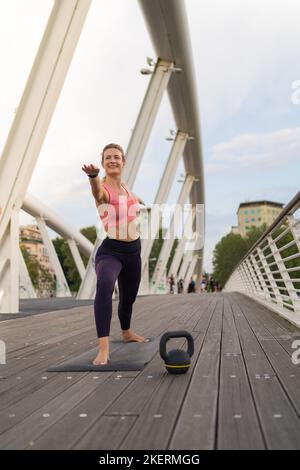 Vue de face de Girl réalisant le yoga au milieu de la ville, posture de guerrier Banque D'Images