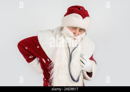 Concept vacances et Noël. Le Père Noël tient un stéthoscope dans sa main - écoute son cœur. Isolé sur blanc Banque D'Images