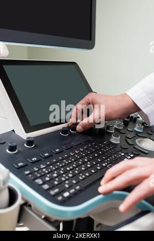 vue partielle du médecin ajustant l'échographe moderne en clinique, image de stock Banque D'Images