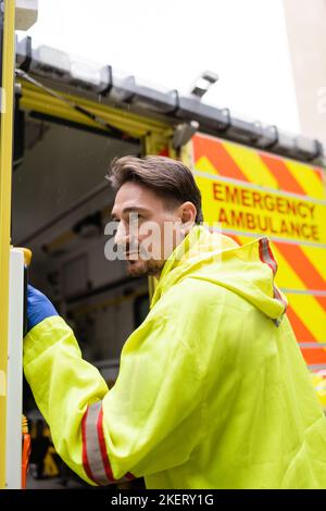 Paramedic en uniforme porte d'ouverture de voiture d'ambulance sur la rue, image de stock Banque D'Images