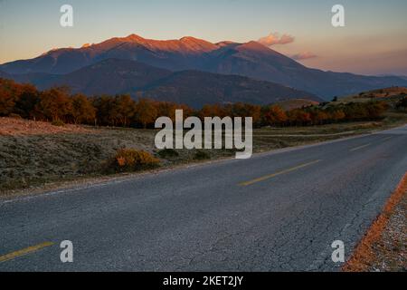 Une route pavée et vide dans le massif du Mont Olympe en Grèce au coucher du soleil Banque D'Images