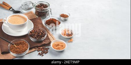 Cappuccino dans une tasse et différents types de café sur fond gris. Banque D'Images
