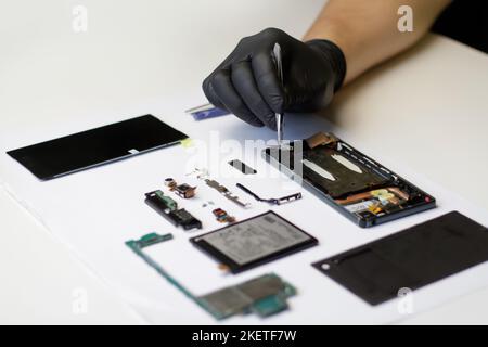 Technicien de mise au point qui répare la carte mère du smartphone dans le laboratoire. Téléphone mobile, électronique, réparation, mise à niveau et technologie. Technicien ou Banque D'Images