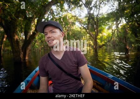 Homme en bateau explorant la forêt sur le lac près de Siem Reap au Cambodge. Banque D'Images