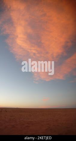 Le violet, le rose et l'orange teinte les nuages dans le ciel bleu au coucher du soleil Banque D'Images