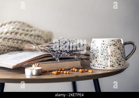 Composition chaleureuse avec une tasse, des livres et des fleurs de lavande séchées. Banque D'Images