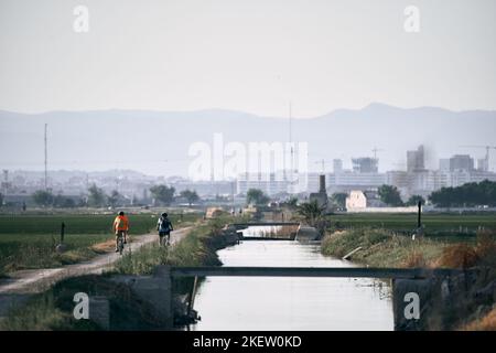 deux hommes caucasiens avec sac à dos à vélo sur la piste cyclable au bord de la rivière, parc naturel d'albufera valence, espagne Banque D'Images