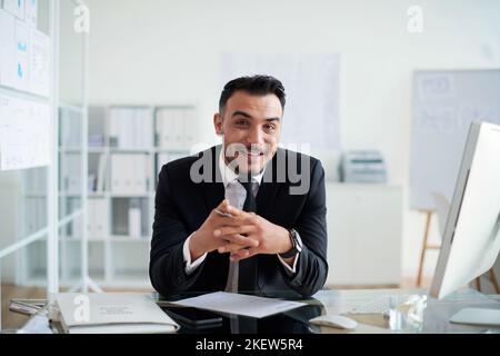 Portrait d'un cadre d'affaires joyeux à sa table au bureau Banque D'Images