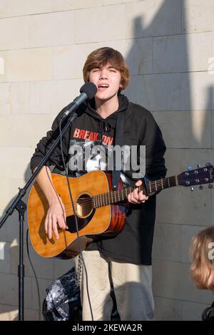 Bender, Moldavie - 12 novembre 2022: Guy jouant de la guitare dans la rue et chantent. Un jeune homme d'apparence européenne avec des cheveux blonds joue la guitare sur le Banque D'Images