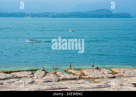 Plage de Sirmione, vue en été des personnes se bronzer sur la plage de Jamaica sur la limite nord de la péninsule de Sirmione, lac de Garde, Lombardie, Italie Banque D'Images