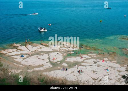 Plage de Sirmione, vue en été des personnes se bronzer sur la plage de Jamaica sur la limite nord de la péninsule de Sirmione, lac de Garde, Lombardie, Italie Banque D'Images