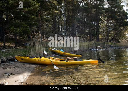 Paire de kayaks de mer jaunes sur la rive d'une île de l'archipel de Stockholm, en Suède. Kayak dans l'archipel suédois, mer Baltique Banque D'Images