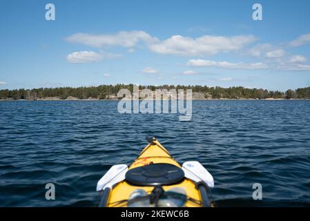 La vue à bord d'un kayak de mer jaune, pagayant à travers les îles de l'archipel suédois de Stockholm, en Suède. Banque D'Images