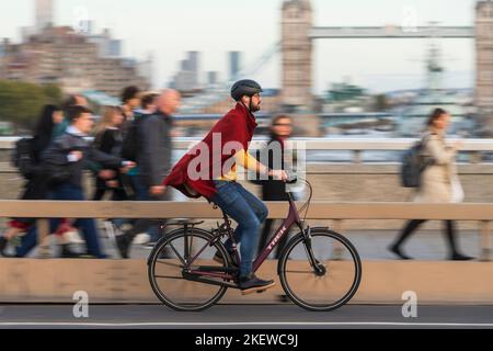 Un homme qui fait du vélo pendant les heures de pointe, traverse le London Bridge, Londres, Royaume-Uni. 18 octobre 2022 Banque D'Images