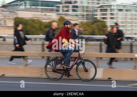 Un homme qui fait du vélo pendant les heures de pointe, traverse le London Bridge, Londres, Royaume-Uni. 18 octobre 2022 Banque D'Images