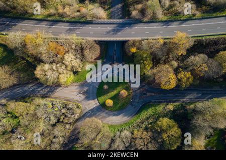 Vue aérienne d'un petit rond-point de circulation sur une route rurale avec des arbres colorés à l'automne. Banque D'Images