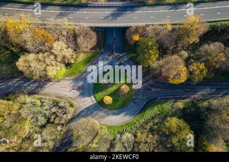 Vue aérienne d'un petit rond-point de circulation sur une route rurale avec des arbres colorés à l'automne. Banque D'Images