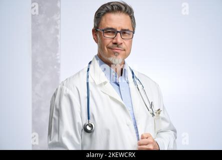 Médecin d'âge moyen en blouse de laboratoire. Médecin amical, généraliste. Adulte moyen, homme d'âge mûr, sourire confiant. Portrait isolé sur blanc. Banque D'Images