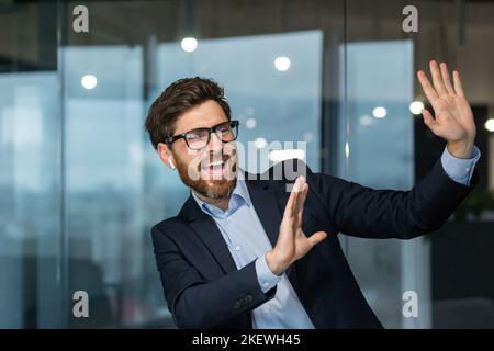 Patron de Manager mature et réussi qui célèbre les bons résultats et les bons résultats au travail, homme dansant au travail à l'intérieur du bureau, homme d'affaires au travail en costume d'affaires. Banque D'Images