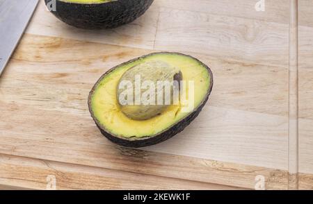 Avocats sur table en bois. Avocat dans un bol. Avocats frais et crus. Banque D'Images