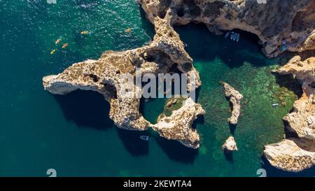 Tir de drone aérien de kayaks et de bateaux passant autour des falaises calcaires magiques de Ponta da Piedade. Exploration des grottes et des tunnels de Lagos Algarve Portugal Banque D'Images