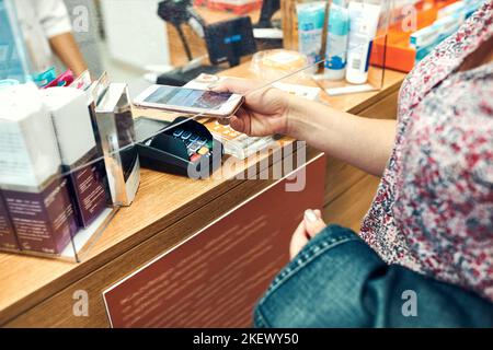 Femme payant des médicaments à la pharmacie en utilisant le mode de paiement sans contact par téléphone portable. Femme utilisant un nouveau mode de paiement Banque D'Images