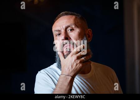 Portrait émotionnel d'un homme adulte aux cheveux gris avec une barbe dans un t-shirt blanc Banque D'Images