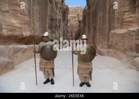 Deux hommes vêtus de soldats romains se tenant au début de siq ou du canyon pour des photos touristiques Petra Jordan Banque D'Images