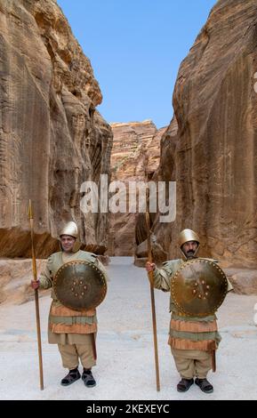 Deux hommes vêtus de soldats romains se tenant au début de siq ou du canyon pour des photos touristiques Petra Jordan 1 Banque D'Images