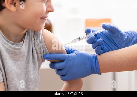 Photo d'un garçon recevant un vaccin à l'hôpital et fermant les yeux Banque D'Images