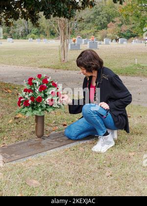 Femme mûre plaçant des fleurs sur un site de sépulture familiale, comme un mémorial, dans un cimetière de Montgomery Alabama, États-Unis. Banque D'Images