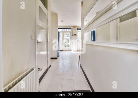 Intérieur moderne plat de style minimaliste avec couloir vide étroit éclairé par des lampes Banque D'Images