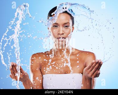 Nettoyage, beauté et eau éclabousse avec femme noire sous la douche et portrait de toilettage sur fond bleu studio. Hygiène, frais et eau avec éclaboussures Banque D'Images