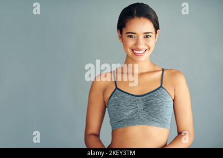 C'est très agréable d'être en forme. Une jeune femme sportive se posant sur un fond gris. Banque D'Images