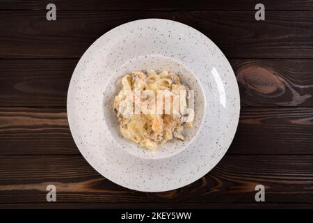 Pâtes italiennes fettuccine aux crevettes et aux musettes dans une sauce crémeuse avec parmesan dans une assiette sur une table en bois. Vue sur le dessus Banque D'Images
