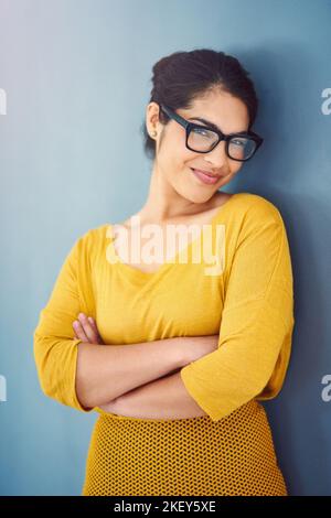 Shes une sorte de verre à moitié plein de penseur. Portrait d'une jeune femme d'affaires ambitieuse posant sur un fond gris. Banque D'Images