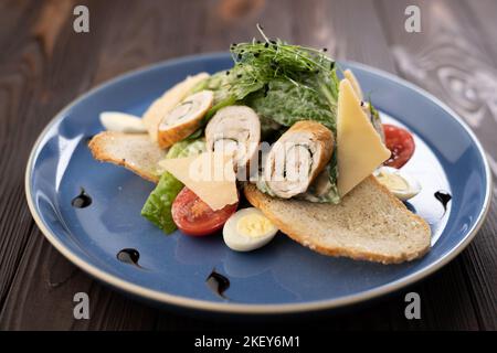 Salade césar gastronomique avec rouleau de poulet grillé sur l'assiette Banque D'Images