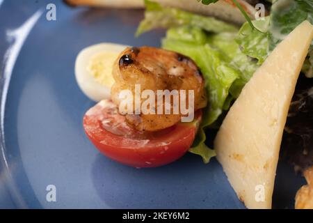 Salade César aux fruits de mer avec crevettes, feuille de salade, croûtons, tomate et parmesan, macro-shot. Banque D'Images