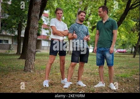 Trois beaux jeunes hommes s'amusent dans un parc Banque D'Images