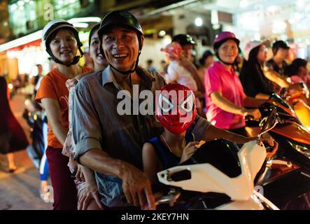 Île de Cat Ba, baie d'Halong, Vietnam ; 22 septembre 2018 : un petit garçon portant un masque Spiderman se déplace avec sa famille sur un scooter dans une rue animée de Cat Banque D'Images