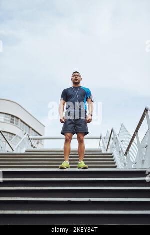 Il est temps d'obtenir le pompage du sang. Photo d'un coureur mâle debout sur les marches de la ville. Banque D'Images