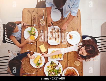 Mère s'assure que tout le monde a. Photo en grand angle d'une famille mangeant de la nourriture maison autour de la table de la salle à manger. Banque D'Images