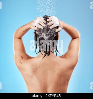 Douche, cheveux et shampooing avec une femme nettoyant en utilisant de l'eau pour le soin des cheveux en studio sur un fond bleu. Hygiène, eau et propreté avec une femme Banque D'Images